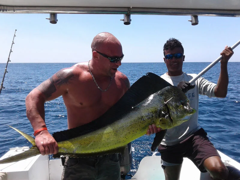 Child holding a fish on a charter boat with smiling captain