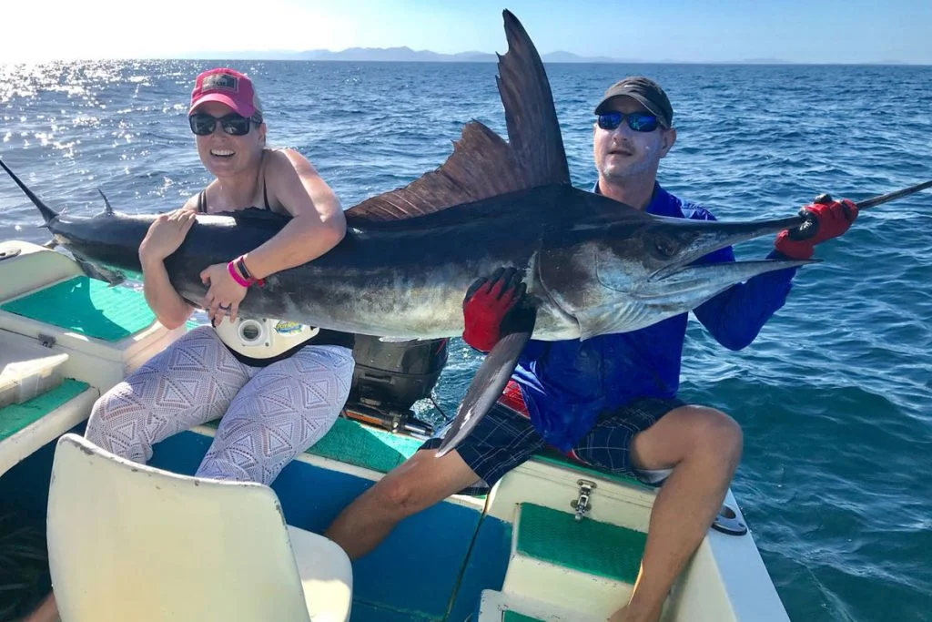 Angler holding a large sailfish alongside the boat